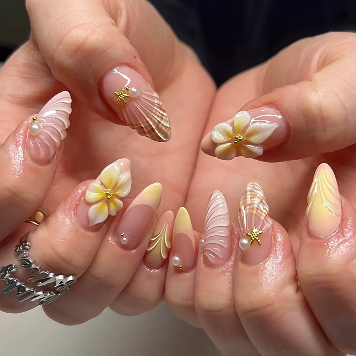 Ongles en amande faits à la main avec dégradé rose nude, décorés de coquillages 3D, de fleurs de fra
