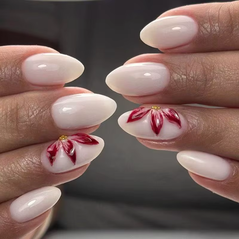 24 faux ongles ovales blancs mats avec décorations de fleurs de lys rouges peintes à la main, un des