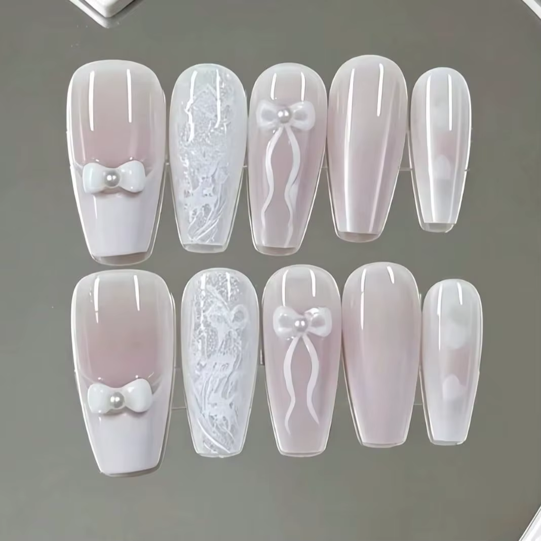 10 faux ongles de longueur moyenne, avec une base dégradée rose nude et blanc laiteux, ornés d'une t