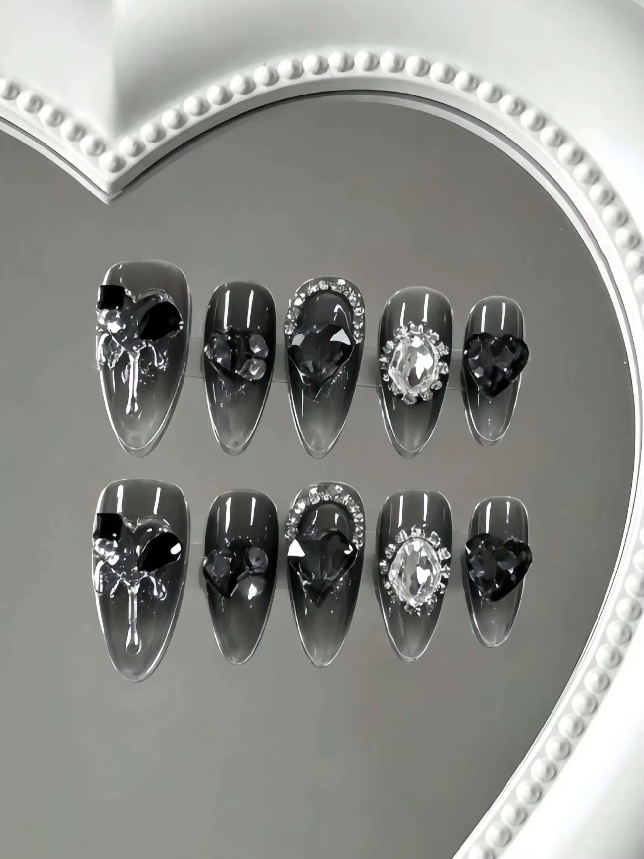 10 faux ongles de longueur moyenne en forme d'amande, tons translucides noir-gris, avec de grands st