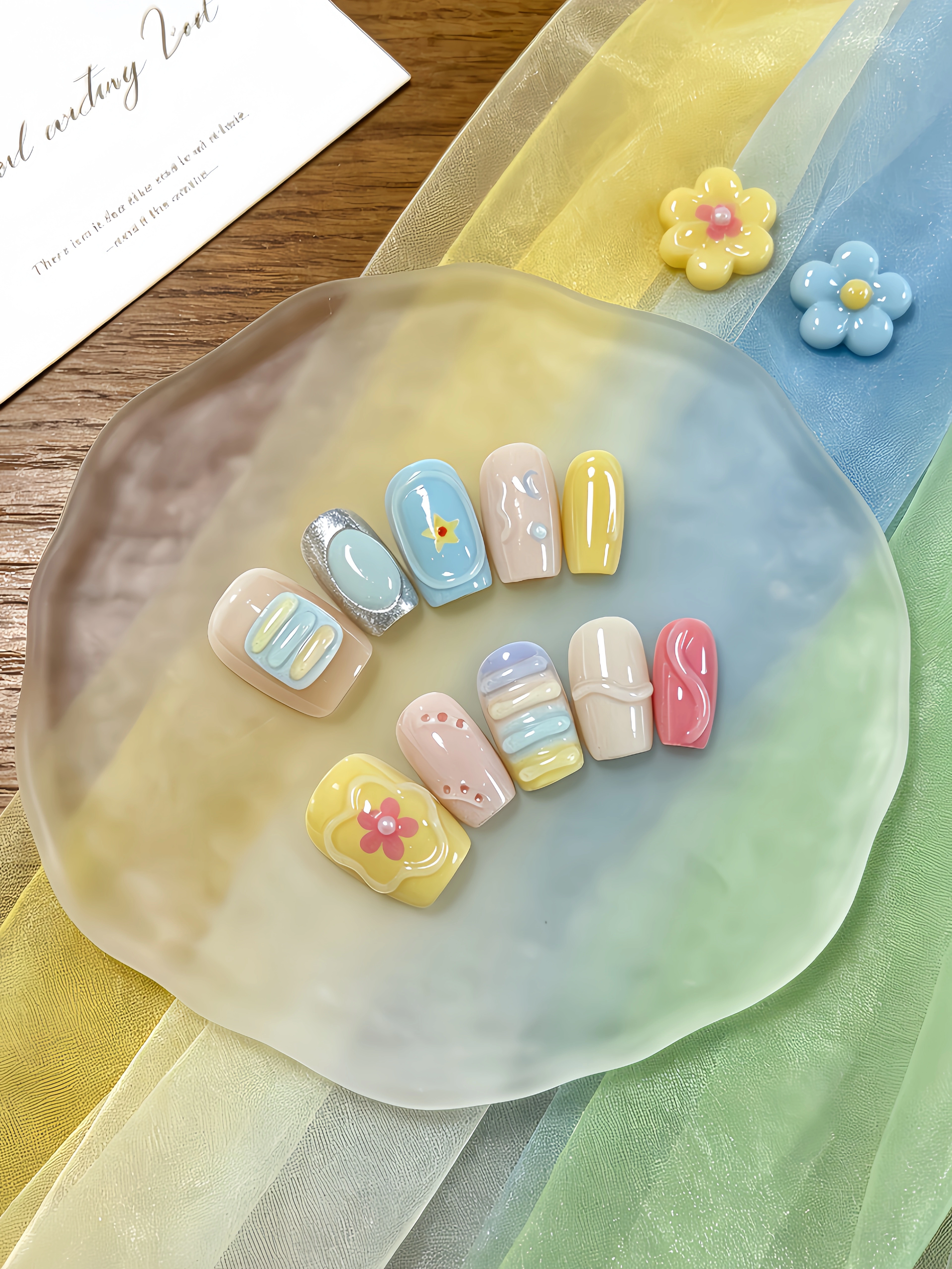 10 ongles courts de forme carrée avec un dégradé multicolore bleu clair, jaune doux, rose nude et ro