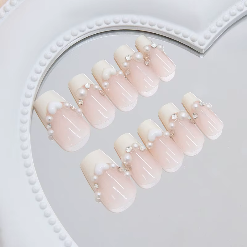Faux ongles courts en press-on jaune crème style ballerine avec perles blanches et strass