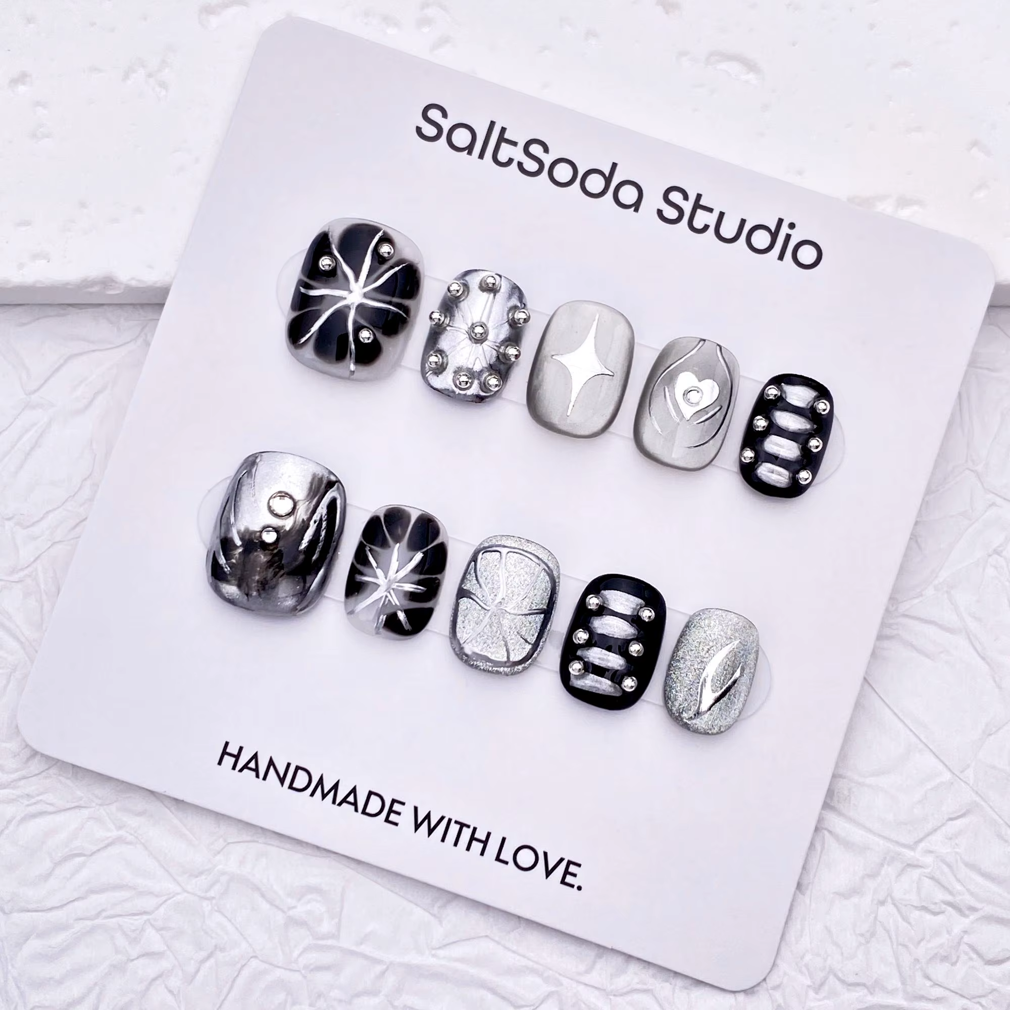Ongles press-on faits main sur le thème des étoiles gothiques ; style "sweet-meets-cool" avec des strass et des accents métalliques
