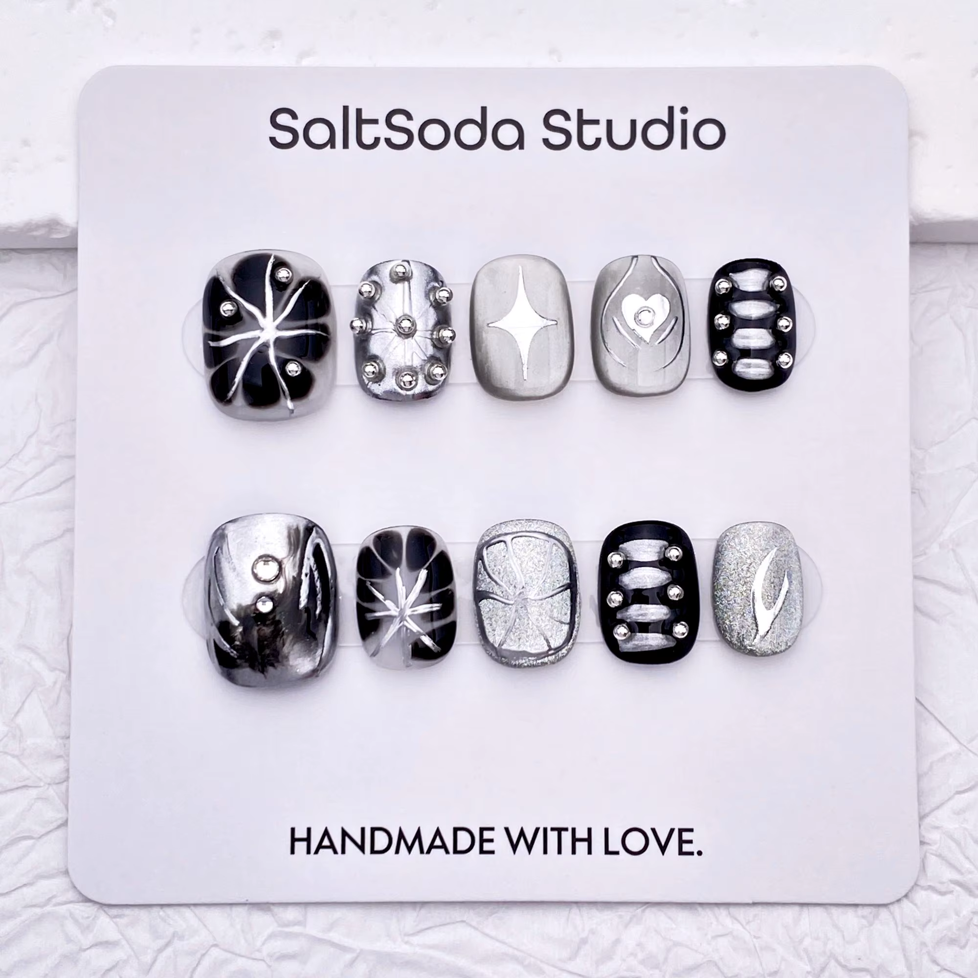 Ongles press-on faits main sur le thème des étoiles gothiques ; style "sweet-meets-cool" avec des strass et des accents métalliques